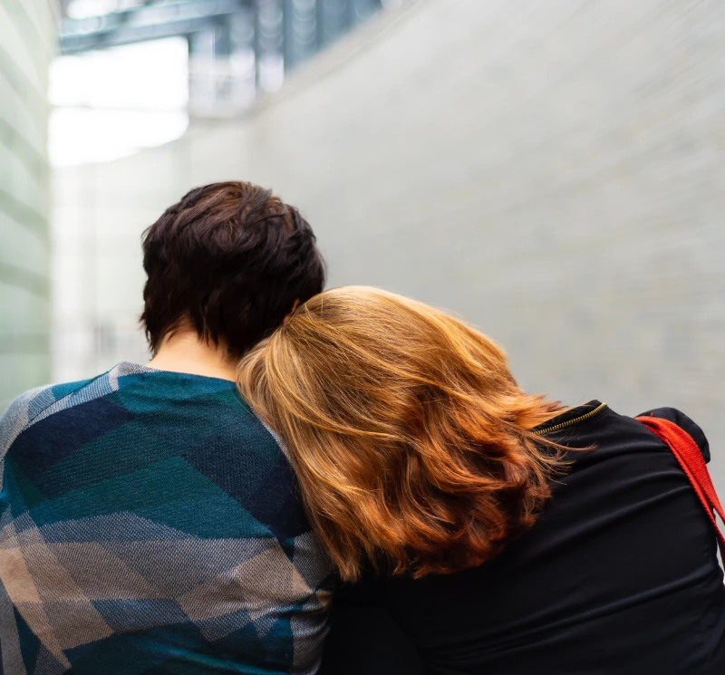 a woman rests her head on another person's shoulder