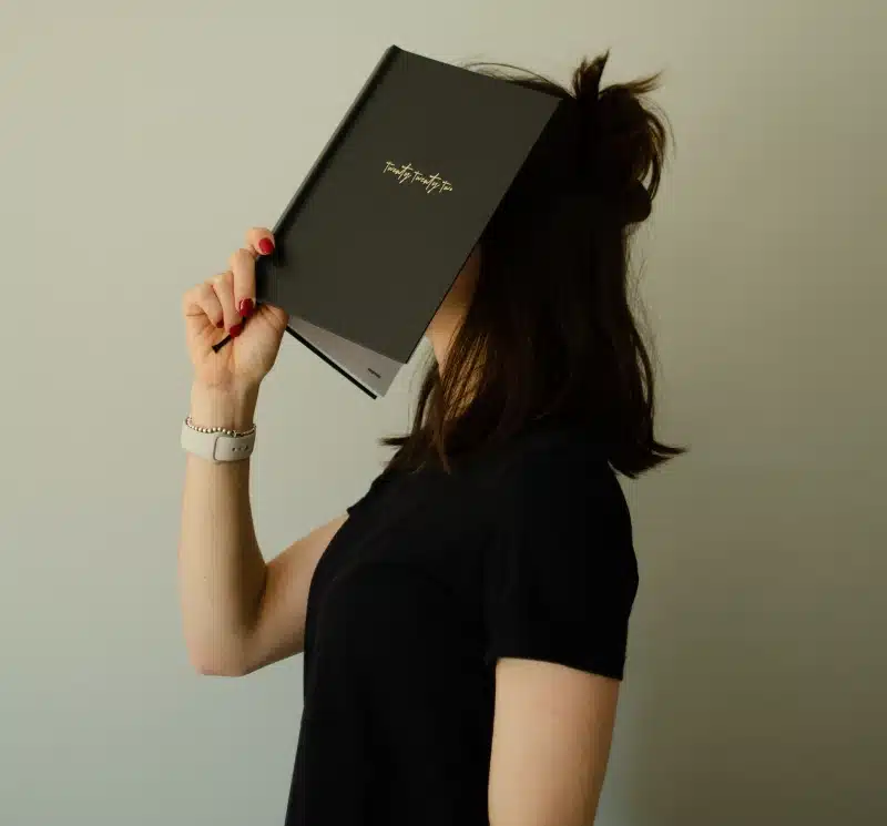 woman hiding behind a book